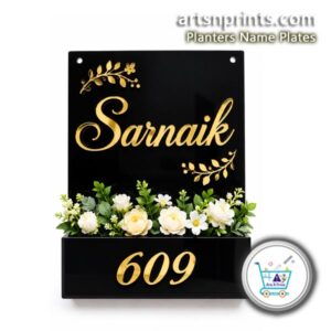Custom A4 size black acrylic house nameplate featuring gold lettering "Sarnaik", house number 609, and white artificial flowers in the built-in planter box.