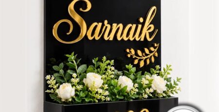 Black A4 acrylic house name plate with custom gold lettering "Sarnaik" and an integrated planter box holding green plants below house number 609.